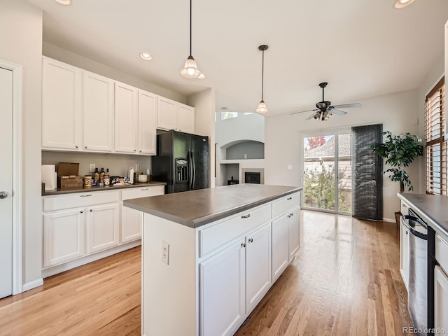 kitchen featuring white cabinets, black refrigerator with ice dispenser, and light wood-type flooring