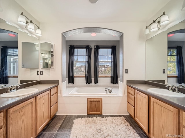 bathroom featuring vanity and a relaxing tiled tub