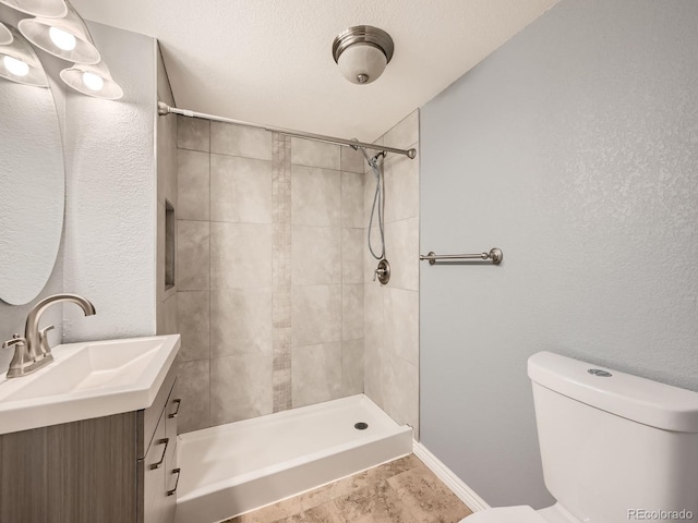 bathroom with vanity, toilet, a textured ceiling, and a tile shower