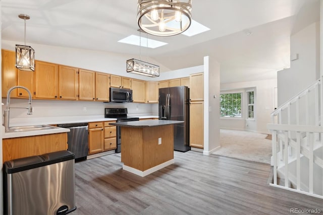 kitchen featuring sink, hanging light fixtures, light wood-type flooring, appliances with stainless steel finishes, and vaulted ceiling with skylight