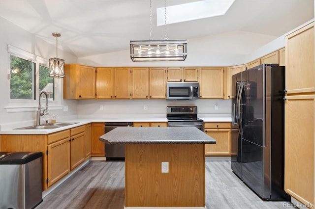 kitchen featuring lofted ceiling with skylight, sink, decorative light fixtures, a center island, and appliances with stainless steel finishes