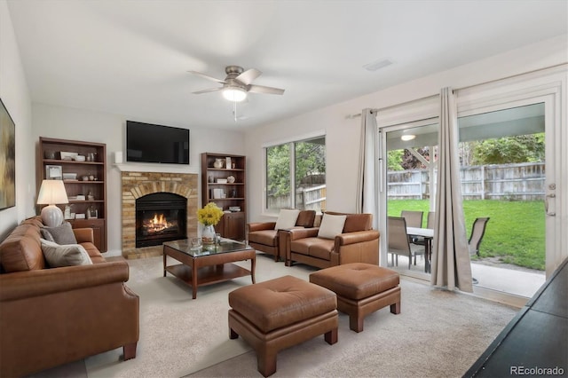 living room featuring ceiling fan, light colored carpet, and a fireplace