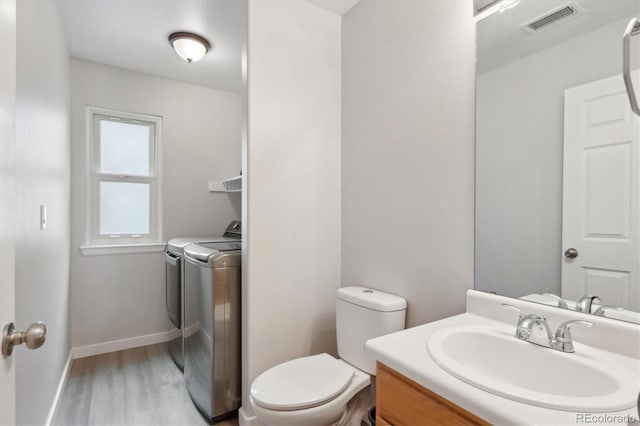 bathroom featuring vanity, wood-type flooring, washing machine and dryer, and toilet