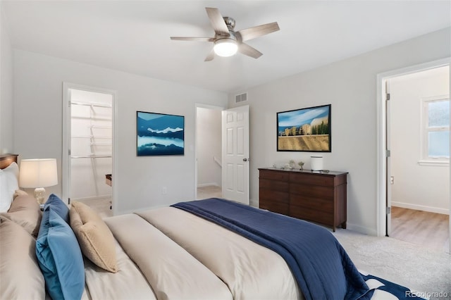 bedroom with connected bathroom, light colored carpet, and ceiling fan