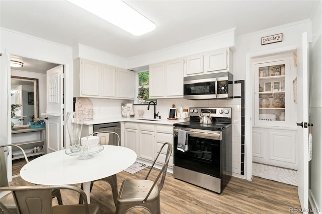 3016 N Franklin St, Denver, CO 80205 - kitchen with stainless steel appliances, decorative backsplash, light countertops, ornamental molding, and light wood-type flooring