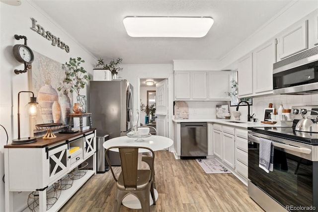 3016 N Franklin St, Denver, CO 80205 - kitchen featuring appliances with stainless steel finishes, ornamental molding, backsplash, light wood finished floors, and white cabinetry