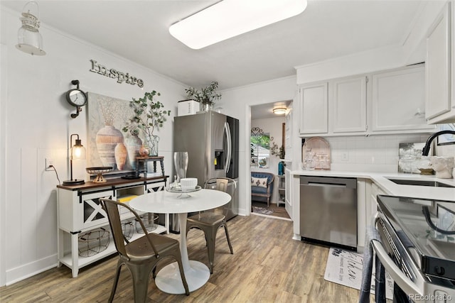 3016 N Franklin St, Denver, CO 80205 - kitchen featuring stainless steel appliances, light wood-type flooring, light countertops, decorative backsplash, and crown molding
