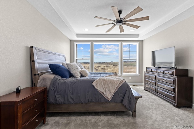 bedroom with ceiling fan, a raised ceiling, and light carpet