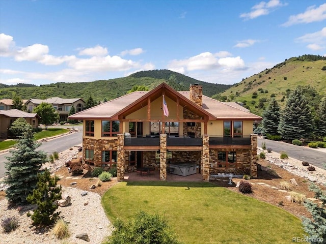 6170 Falcon Ridge Ln, Morrison, CO 80465 - rear view of property featuring stone siding, a mountain view, a hot tub, a patio area, and a yard