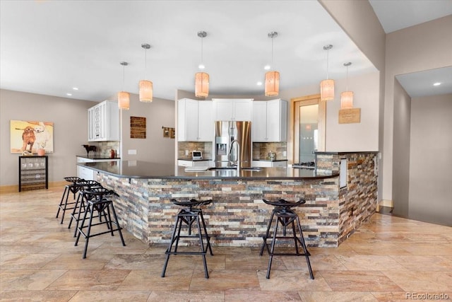 6170 Falcon Ridge Ln, Morrison, CO 80465 - kitchen featuring dark countertops, stainless steel fridge, tasteful backsplash, a kitchen bar, and white cabinets
