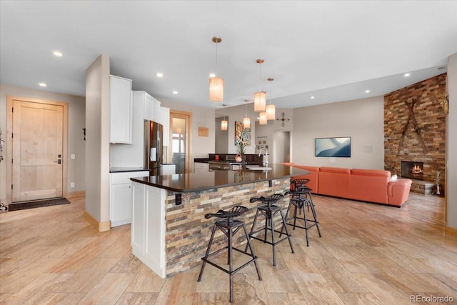 6170 Falcon Ridge Ln, Morrison, CO 80465 - kitchen with dark countertops, stainless steel refrigerator, white cabinets, recessed lighting, and a breakfast bar area