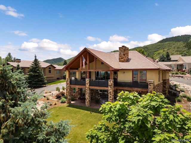 6170 Falcon Ridge Ln, Morrison, CO 80465 - rear view of house with a mountain view, stone siding, a yard, a tiled roof, and a chimney