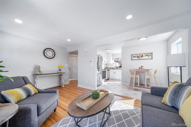 living area with recessed lighting, light wood-style flooring, and baseboards