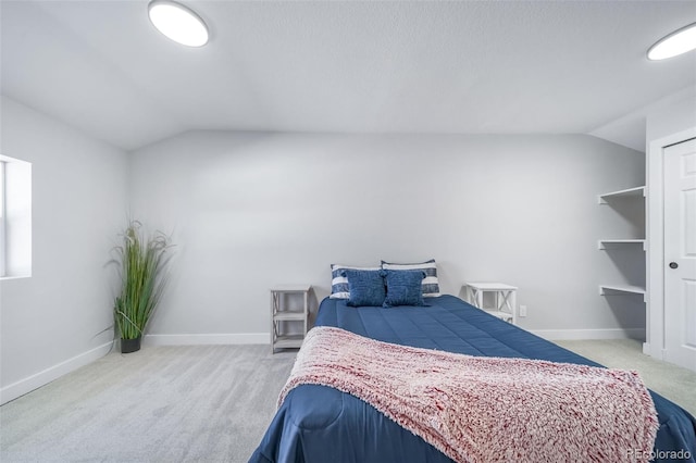 carpeted bedroom featuring lofted ceiling and baseboards