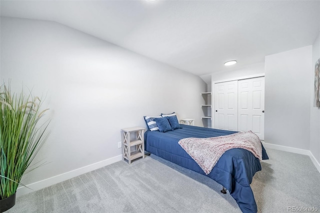 bedroom with lofted ceiling, a closet, baseboards, and light colored carpet