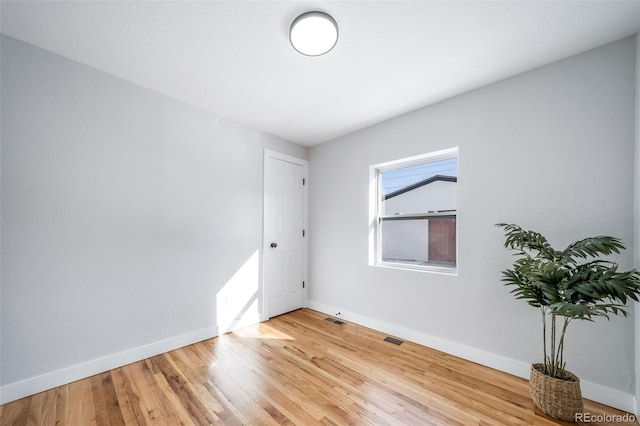 empty room with baseboards, visible vents, and wood finished floors