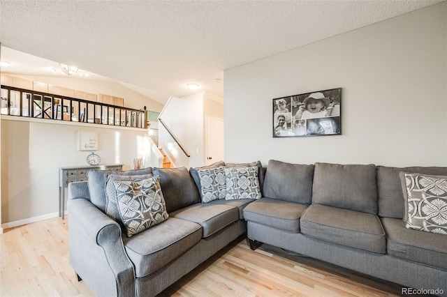 living room with a textured ceiling, light hardwood / wood-style flooring, and lofted ceiling