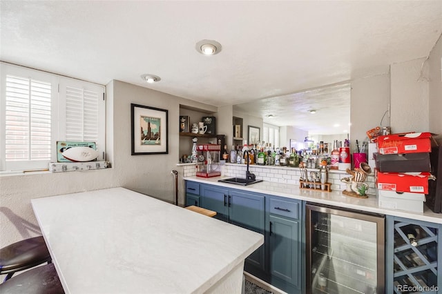 bar with backsplash, a textured ceiling, blue cabinets, sink, and wine cooler