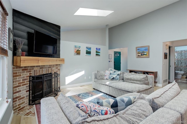 living area with a brick fireplace, wood finished floors, a skylight, high vaulted ceiling, and baseboards