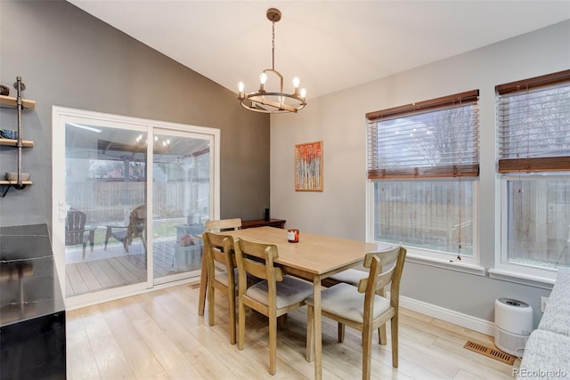 dining space featuring a chandelier, light wood-type flooring, vaulted ceiling, and baseboards