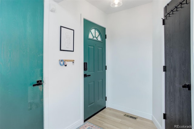 foyer entrance with light wood-style flooring and baseboards