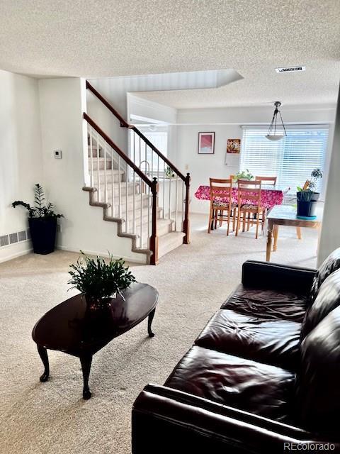 21030 E 39th Ave, Denver, CO 80249 - carpeted living room with visible vents, a textured ceiling, and stairs