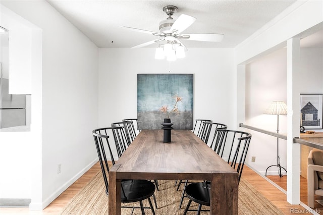 dining space with ceiling fan, light wood finished floors, and baseboards