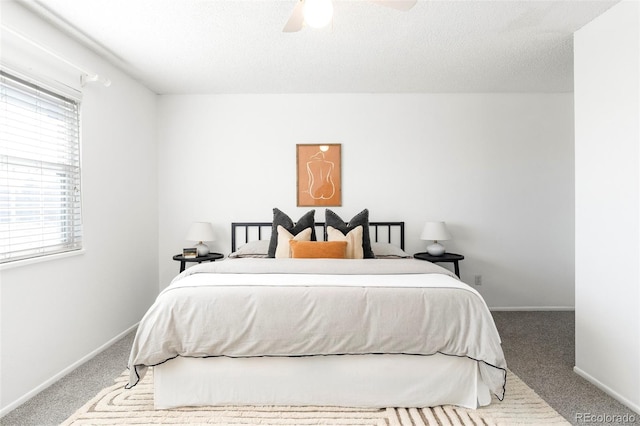 carpeted bedroom with a textured ceiling, ceiling fan, and baseboards