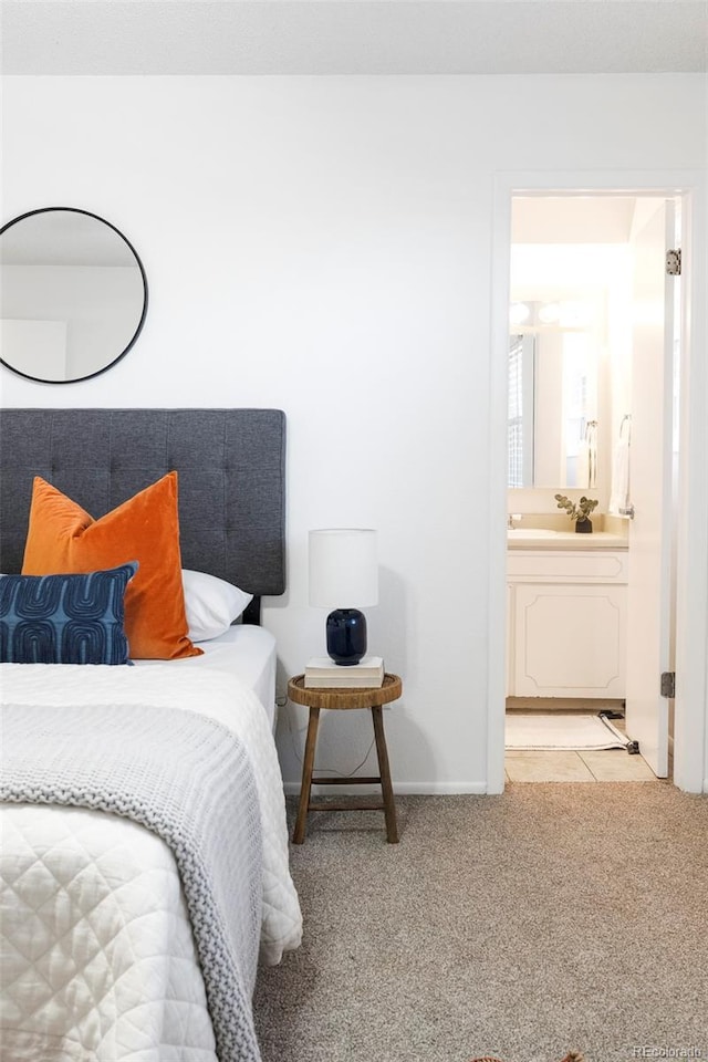 bedroom featuring baseboards, connected bathroom, and light colored carpet