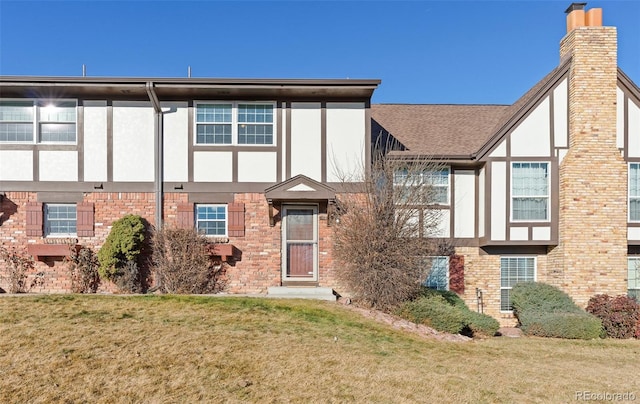 view of front of home featuring brick siding, a front lawn, and stucco siding