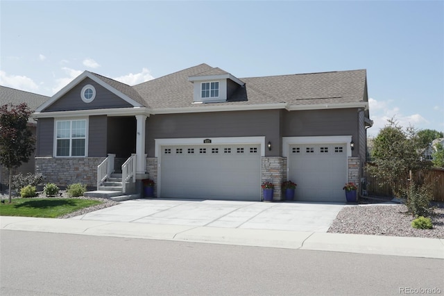 craftsman-style home featuring a garage, driveway, roof with shingles, and stone siding