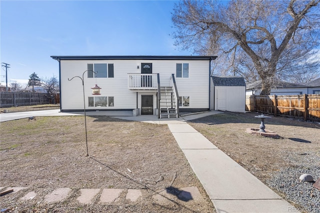 view of front of home featuring a patio, a shed, a fenced backyard, an outdoor structure, and stairs