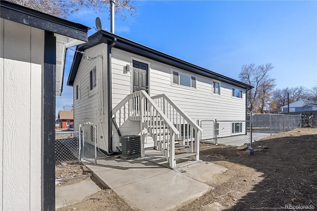 back of property featuring a gate, fence, and central AC