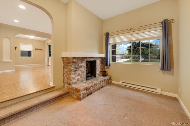 unfurnished living room with a baseboard heating unit, hardwood / wood-style flooring, and a brick fireplace