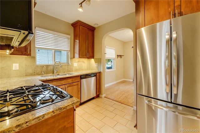 kitchen featuring appliances with stainless steel finishes, light stone countertops, sink, and a wealth of natural light