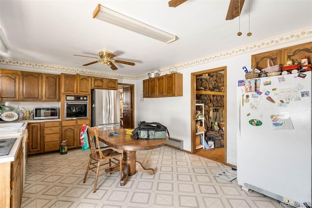 kitchen featuring stainless steel appliances, a ceiling fan, light floors, and brown cabinets