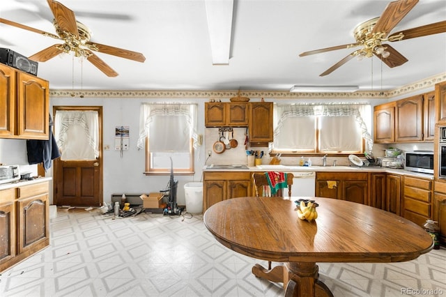 kitchen with a ceiling fan, light floors, stainless steel microwave, and light countertops