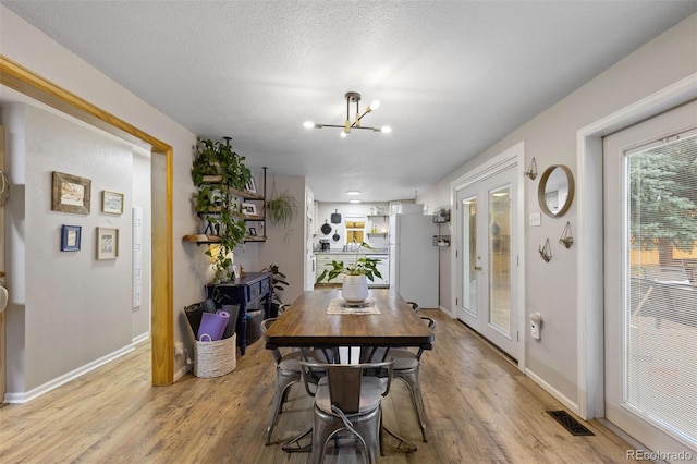 26095 Columbine Trl, Kittredge, CO 80457 - dining area featuring a chandelier, a textured ceiling, light wood-style flooring, baseboards, and visible vents