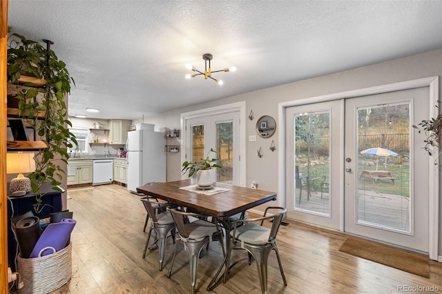 26095 Columbine Trl, Kittredge, CO 80457 - dining room featuring french doors, a notable chandelier, light wood-style floors, and a textured ceiling