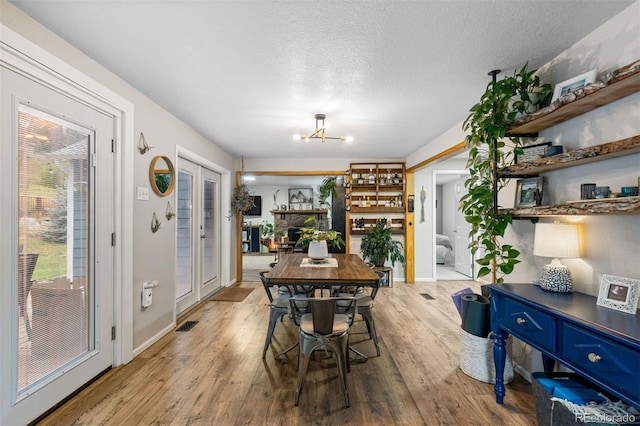 26095 Columbine Trl, Kittredge, CO 80457 - dining space featuring baseboards, a textured ceiling, wood finished floors, and a chandelier