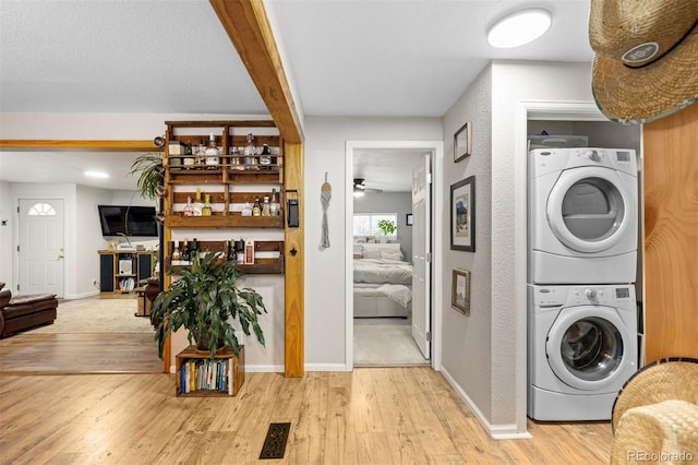26095 Columbine Trl, Kittredge, CO 80457 - clothes washing area featuring stacked washer and clothes dryer, baseboards, laundry area, and wood finished floors