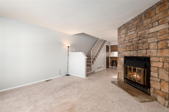 unfurnished living room featuring a stone fireplace, light colored carpet, and a textured ceiling