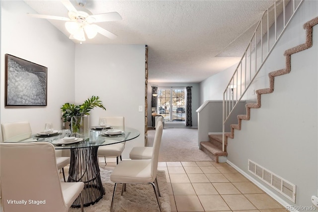 tiled dining space with ceiling fan and a textured ceiling