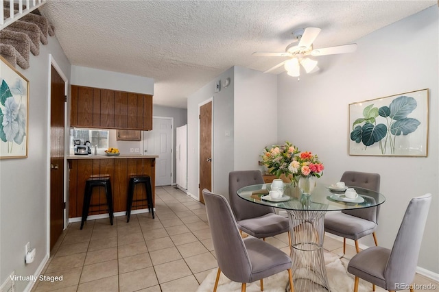 tiled dining room featuring a textured ceiling and ceiling fan