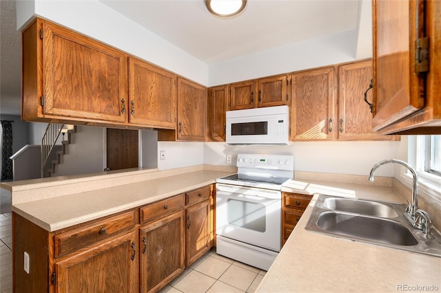 kitchen featuring sink, white appliances, light tile patterned floors, and kitchen peninsula