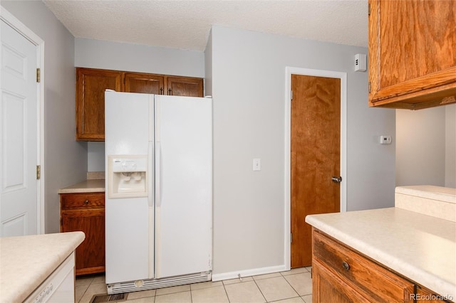 kitchen with light tile patterned flooring, a textured ceiling, and white fridge with ice dispenser