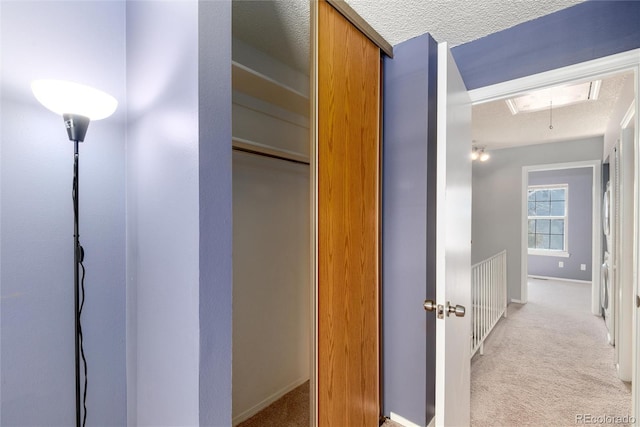 hallway with light colored carpet and a textured ceiling