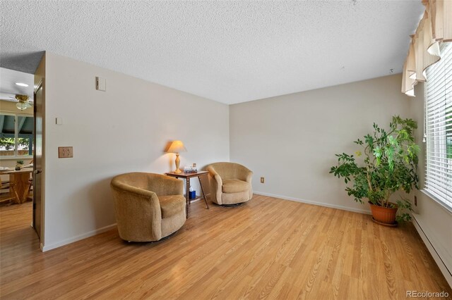 4525 S Cole Ct, Morrison, CO 80465 - living area with light wood-type flooring, a baseboard heating unit, a textured ceiling, baseboards, and a ceiling fan