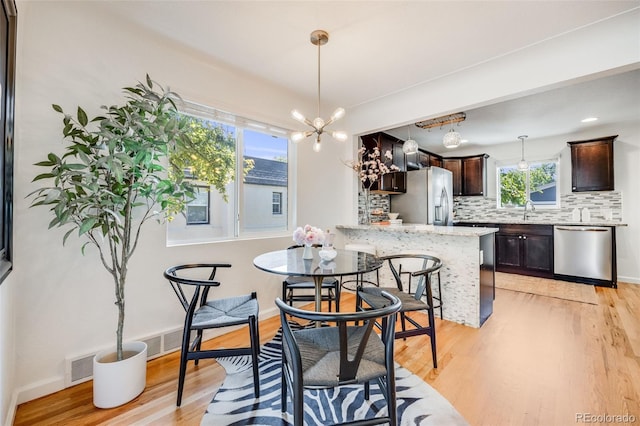 1765 Xenia St, Denver, CO 80220 - dining room with light wood finished floors, a chandelier, and baseboards