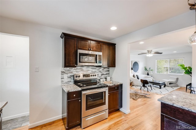 1765 Xenia St, Denver, CO 80220 - kitchen featuring appliances with stainless steel finishes, dark brown cabinets, decorative backsplash, light wood finished floors, and light stone counters